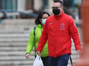Two people wear masks while walking in public on Winnipeg on Friday, Oct. 22, 2021.