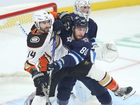 Winnipeg Jets centre Pierre-Luc Dubois (centre) ties up Anaheim Ducks centre Adam Henrique in front of goaltender Connor Hellebuyck in Winnipeg on Thursday, Oct. 21, 2021.