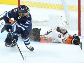 Anaheim Ducks defenceman Jamie Drysdale (right) dives across an empty net in an attempt to stop a shot from Winnipeg Jets forward Kyle Connor that hit the post in Winnipeg on Thursday, Oct. 21, 2021.