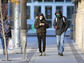People wearing masks walk along Hargrave Avenue in downtown Winnipeg on Monday, Oct. 25, 2021.