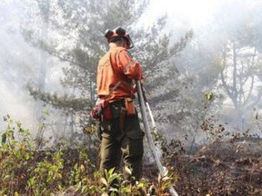 An Ontario fire ranger can be seen dousing a hot spot this July. SUBMITTED PHOTO