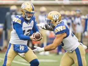 Winnipeg Blue Bombers quarterback Sean McGuire hands off to running back Brady Oliveira during first half CFL football action against the Montreal Alouettes, in Montreal, Saturday, Nov. 13, 2021.