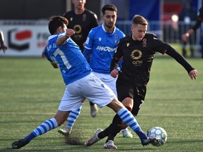 FC Edmonton Hunter Gorskie (27) tries to knock the ball away from Valour FC Moses Dyer (7) during Canadian Premier League soccer action at Clarke Field in Edmonton, November 6, 2021.