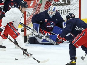 Jets forward Nikolaj Ehlers (left) watches a loose puck at practice yesterday. Ehlers’ father, Team Denmark coach Heinz Ehlers, was in the stands at practice yesterday to size up his son’s skills for the 2022 Beijing Olympics.  KEVIN KING/Winnipeg Sun