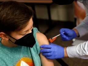 In this file photo taken on May 13, 2021, a young person receives the Pfizer-BioNTech COVID-19 Vaccine from a pharmacist in Bloomfield Hills, Mich.