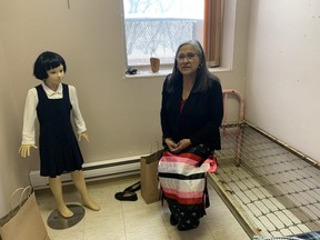 Lorraine Daniels, the executive director of the National Indian Residential School Museum of Canada, is seen with a display at the museum that shows a typical bed a child would have had to sleep on at a residential school, as well as a mannequin of a young child wearing a typical uniform from a residential school. Dave Baxter/Winnipeg Sun
