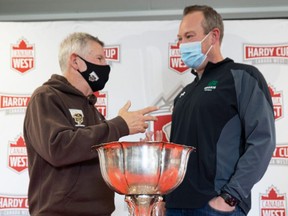 Manitoba Bisons head coach Brian Dobie (left) and Saskatchewan Huskies head coach Scott Flory stand for a photo with the Hardy Cup trophy during a news conference on Nov. 19, 2021.