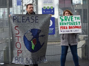 Protestors hold a banner calling against Brazil's President Jair Bolsonaro as they demonstrate near the Scottish Event Campus (SEC), the venue of the COP26 UN Climate Change Conference in Glasgow, Scotland on November 2, 2021. - World leaders meeting at the COP26 climate summit in Glasgow will issue a multibillion-dollar pledge to end deforestation by 2030 but that date is too distant for campaigners who want action sooner to save the planet's lungs. (Photo by ANDY BUCHANAN / AFP)