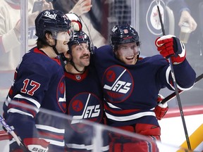 Nov 13, 2021; Winnipeg, Manitoba, CAN; Winnipeg Jets left wing Adam Lowry (17) and center Andrew Copp (9) celebrate the third period goal of defenseman Dylan DeMelo (2) against the Los Angeles Kings at Canada Life Centre. Mandatory Credit: James Carey Lauder-USA TODAY Sports