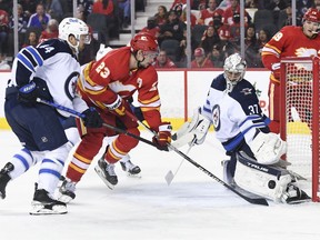 Winnipeg Jets goalie Connor Hellebuyck (37) stops a shot in front of Calgary Flames forward Sean Monahan (23) in the third period at Scotiabank Saddledome in Calgary on Nov. 27, 2021. The Jets won 4-2.