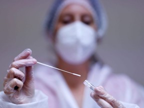 A medical worker holds a test tube after administering a nasal swab.
