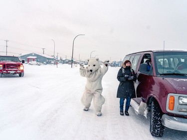 A person dressed as a polar bear waits at the finish line of the Polar Bear Marathon, where runners need a car following them to watch for polar bears, in Churchill, Man., on Nov. 20, 2021.