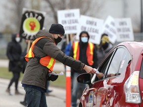 A man hands out an information pamphlet in front of the University of Manitoba Faculty Association picket line on University Crescent in Winnipeg on Tuesday, Nov. 2, 2021.
