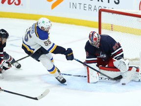 Winnipeg Jets goaltender Connor Hellebuyck (right) makes a stop on St. Louis Blues defenceman Colton Parayko during overtime in Winnipeg on Tues., Nov. 9, 2021.  KEVIN KING/Winnipeg Sun/Postmedia Network