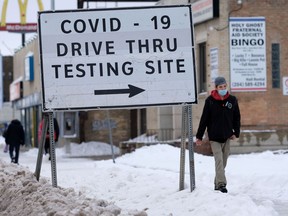 A person wears a mask while walking past a sign for a Covid-19 test site in Winnipeg on Tuesday Nov. 16. 2021 Chris Procaylo/Winnipeg Sun