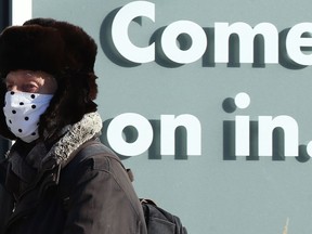 A man wearing a mask walks past a cannabis store on Osborne Street in Winnipeg on Wed., Nov. 24, 2021.  KEVIN KING/Winnipeg Sun/Postmedia Network