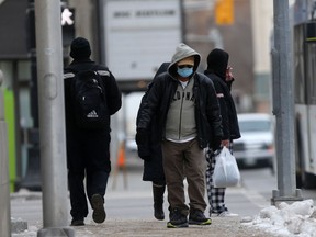 A person wears a mask while walking along a sidewalk in Winnipeg on Friday Nov. 26. 2021.