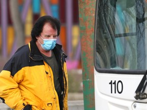 A man wearing a mask about to board a bus at Confusion Corner in Winnipeg on Monday, Nov. 29, 2021.