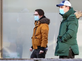 People wearing masks walk along Main Street near Portage Avenue in Winnipeg on Monday, Nov. 29, 2021.