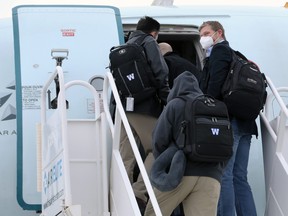 Head coach Mike O'Shea (right) looks back as the Winnipeg Blue Bombers board a plane at Winnipeg International Airport.