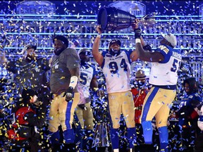 Jackson Jeffcoat (94) and Jermarcus Hardrick (51) of the Winnipeg Blue Bombers celebrate victory with the Grey Cup following the 108th Grey Cup CFL Championship Game against the Hamilton Tiger-Cats at Tim Hortons Field on Dec. 12, 2021 in Hamilton. The game and the celebration happened in the nick of time as Ontario has now put restrictions on attendance at sporting events.