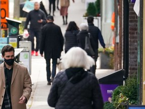 A man wearing a face mask walks along Yonge Street in Toronto on November 4, 2021.