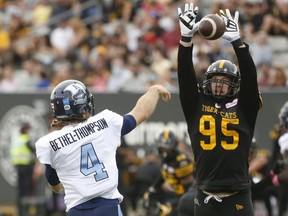 Toronto Argonauts quarterback McLeod Bethel-Thompson deals with defensive end Julian Howsare of the Hamilton Tiger Cats during a CFL game in Hamilton on Oct. 11, 2021. Jack Boland/Toronto Sun/Postmedia Network