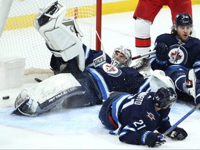 Winnipeg Jets goaltender Connor Hellebuyck has a crowd in the crease, but cannot prevent a goal from the Carolina Hurricanes in Winnipeg on Dec. 7, 2021.