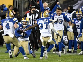 Winnipeg Blue Bombers players react as linebacker Kyrie Wilson (19, second left) holds the ball after making an interception in overtime to clinch the victory over the Hamilton Tiger-Cats in the 108th Grey Cup football game at Tim Hortons Field on Dec. 12, 2021.