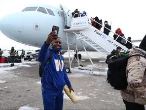 Blue Bombers defensive back Nick Taylor grabs some footage as the team boards a plane at Winnipeg International Airport yesterday.