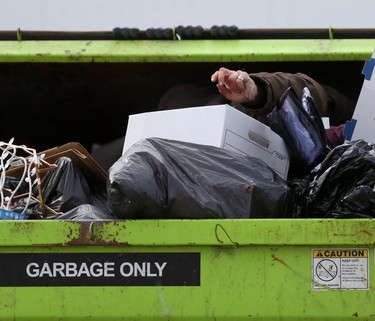 A person digs through a dumpster in downtown Winnipeg on March 3. Chris Procaylo/Winnipeg Sun