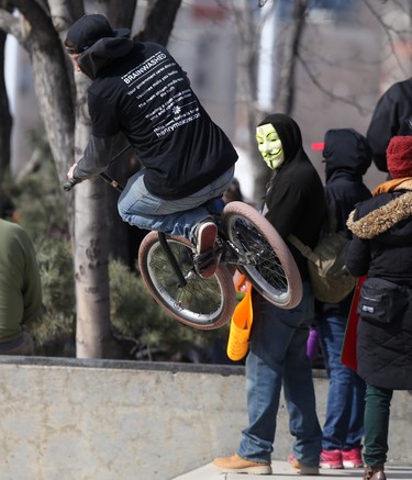 Tyler flies through the air at The Forks, while a person wearing a mask looks on, in Winnipeg on March 20. Chris Procaylo/Winnipeg Sun