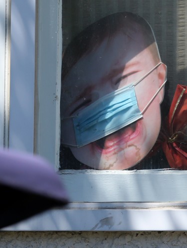 A surgical mask is stretched across a cut out picture of a screaming baby, in a window, in Winnipeg on June 22. Chris Procaylo/Winnipeg Sun