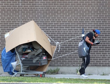 A person pulls a shopping cart full of items along a sidewalk in Winnipeg on July 10. Chris Procaylo/Winnipeg Sun