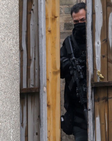 A person wears a mask and holds an automatic rifle with a silencer near where a person suffered a gunshot wound in Winnipeg on October 27. Chris Procaylo/Winnipeg Sun