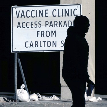A man carrying a drink is silhouetted in front of a sign for the COVID-19 vaccination site at RBC Convention Centre in Winnipeg on Tues., Nov. 9, 2021.  KEVIN KING/Winnipeg Sun/Postmedia Network
