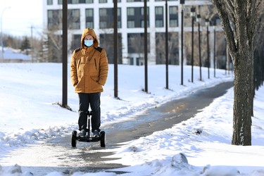 A man wearing a mask rides an electric scooter along Chancellor Matheson Boulevard in Winnipeg on Thurs., Nov. 18, 2021.  KEVIN KING/Winnipeg Sun/Postmedia Network