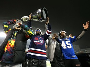 Winston Rose holds the trophy while DeAundre Alford (45) basks in the moment as the Winnipeg Blue Bombers celebrated its 2021 Grey Cup win at IG Field on Dec. 15, 2021.
