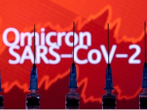 Syringes with needles are seen in front of a displayed stock graph and words "Omicron SARS-CoV-2" in this illustration taken, November 27, 2021.