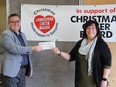 Troy Hamilton, President of Maxim Truck and Trailer presents a cheque for $12,242 to Shawna Bell, Executive Director of The Christmas Cheer Board at the Christmas Cheer Board's temporary warehouse in Winnipeg on Wednesday, Dec. 22, 2021.
