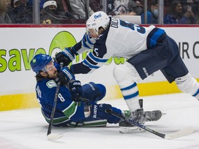 Winnipeg Jets defenceman Brenden Dillon (5) checks Vancouver Canucks forward Conor Garland (8) to the ice in the first period at Rogers Arenain Vancouver on Dec. 10, 2021.
