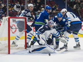 Vancouver Canucks forward Tanner Pearson (70) and Winnipeg Jets forward Adam Lowry (17) watch goalie Eric Comrie (1) control the rebound in the first period at Rogers Arena in Vancouver on Dec. 10, 2021.