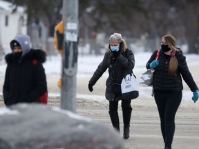 A group of people wear masks while crossing a street in Winnipeg on Tuesday, Dec. 7. 2021.