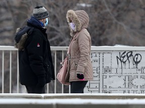 Two people wear masks while walking across a bridge in Winnipeg on Dec. 7, 2021. Chris Procaylo/Winnipeg Sun