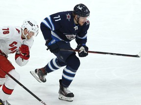 Winnipeg Jets forward Evgeny Svechnikov (right) skates with Carolina Hurricanes forward Steven Lorentz giving chase in Winnipeg on Tuesday, Dec. 7, 2021.