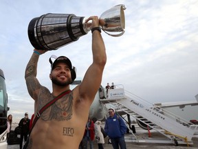 Running back Brady Oliveira hoists the Grey Cup at Winnipeg International Airport as the Winnipeg Blue Bombers returned home as back-to-back CFL champions on Monday, Dec. 13, 2021.