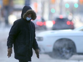 A person wears a mask while crossing a street in Winnipeg during the COVID-19 pandemic on Saturday, Dec. 18. 2021.