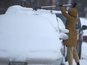 A person clears fresh snow from a vehicle in Winnipeg.