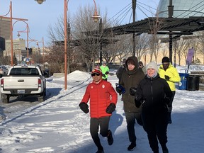 Winnipeg ultramarathon runner Junel Malapad (in red) passes the Canadian Museum for Human Rights with some of his supporting runners as his sixth annual Change Boxing Day to Running Day event in support of Siloam Mission begins on Sunday. This year's run will look a little different as he attempts to run 200 kilometres over 48 hours.