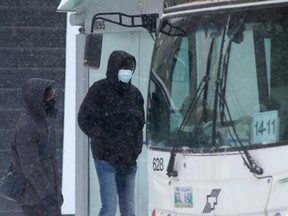 Two people wear masks while boarding a transit bus in Winnipeg on Tuesday, Dec. 28. 2021.